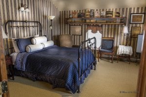 bedroom with iron bed with blue bedspread, 2 chairs