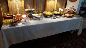 table with white tablecloth filled with breakfast foods