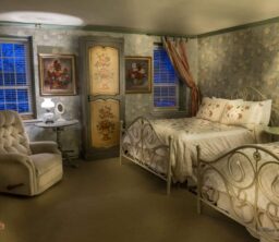 bedroom with floral wallpaper and 2 beds, lamps, recliner