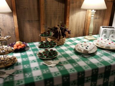 table decorated for St. Patrick's Day with green and white tablecloth and pastries