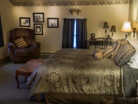 bed with brown bedspread, recliner, lamp