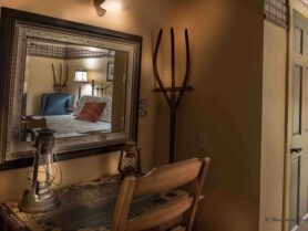 room with brown walls, desk and chair, mirror reflecting bed