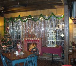 table and chairs next to wall decorated for Christmas with tree and fireplace