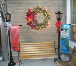 bench between 2 lanterns with wreath above