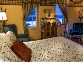 bedroom with iron bed with white and red bedspread, chairs