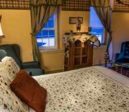 bedroom with iron bed with white and red bedspread, chairs