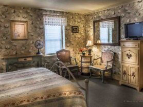 room with floral wallpaper, bed, rocke