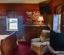 The Major Leaguer room with bed, chest of drawers, comfy chair and small fridge