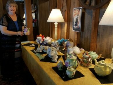 lady holding teapot next to table with teapots