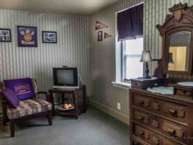 room with dresser, tv, chair, striped wallpaper